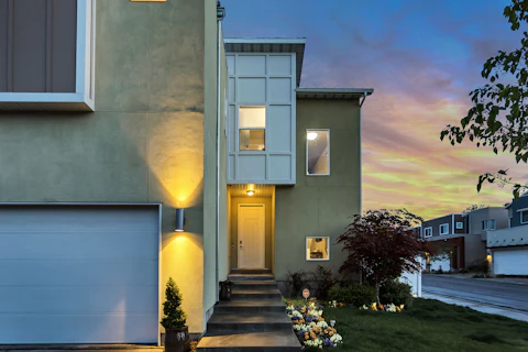 Modern residential exterior with a warmly lit entrance at dusk